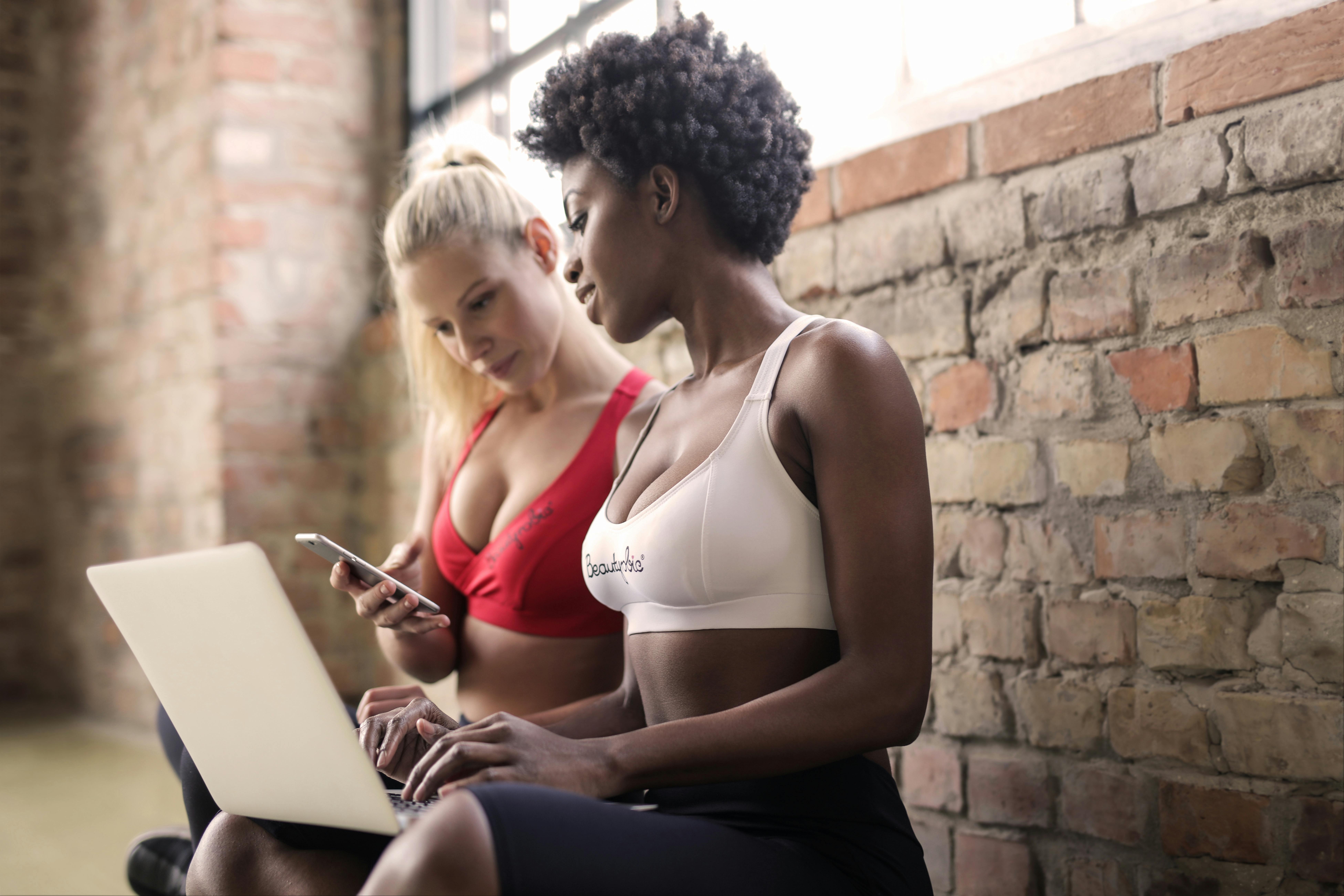 two women looking at a laptop in gym clothing