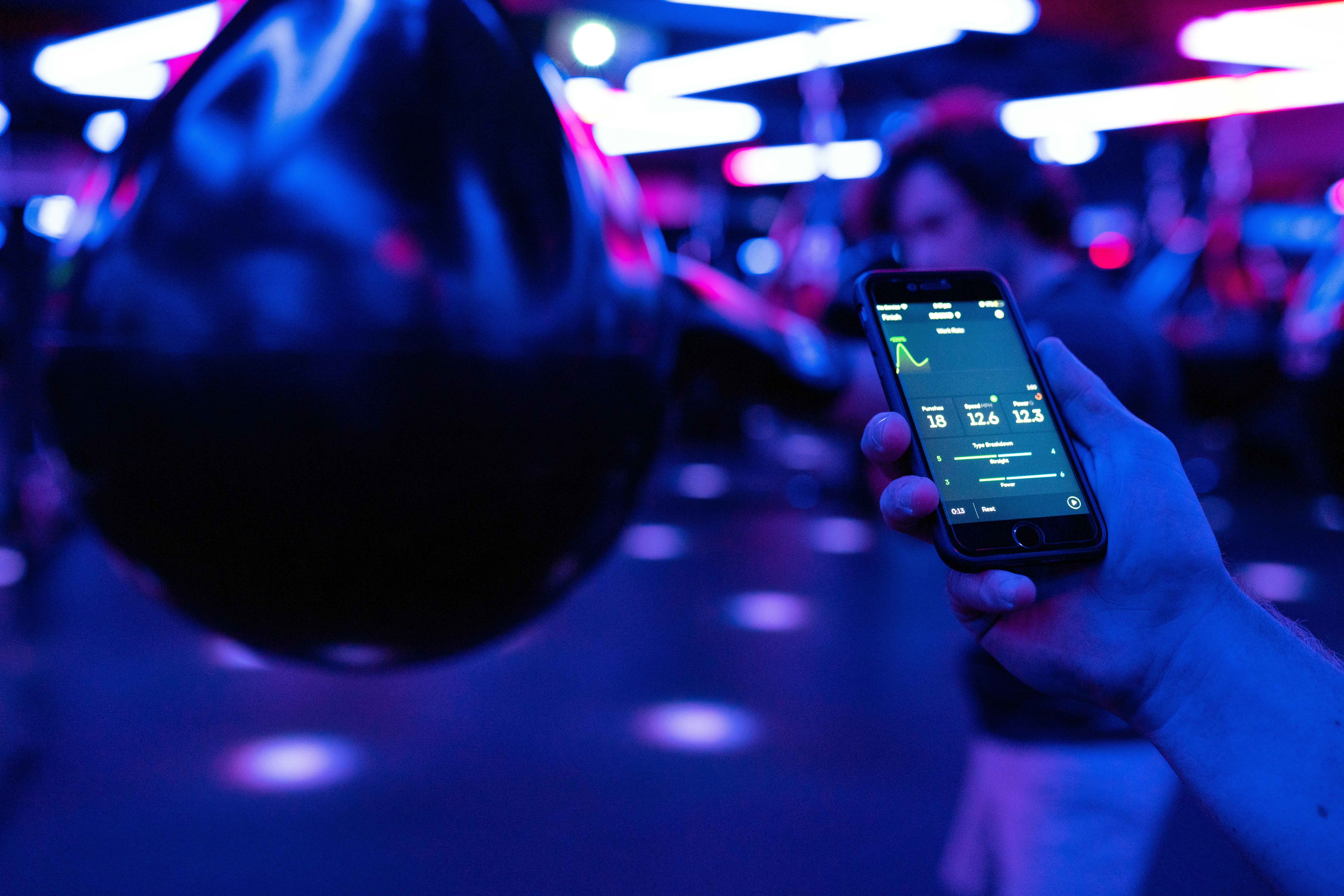 hand holing a phone in a gym looking at statistics on a screen