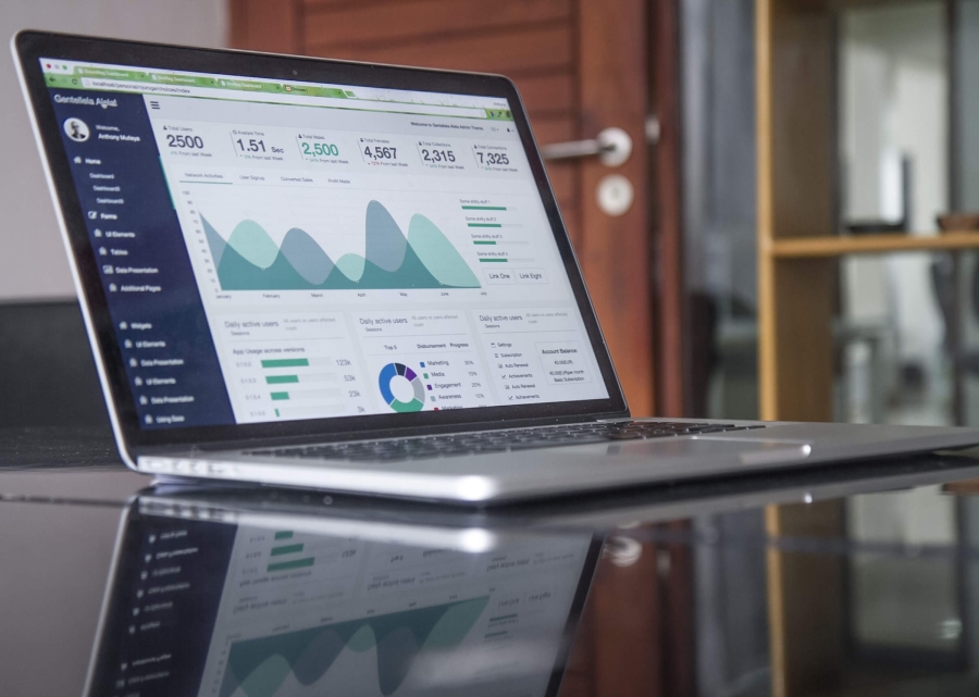 an open laptop sitting on a glass table showing statistics and digital reports