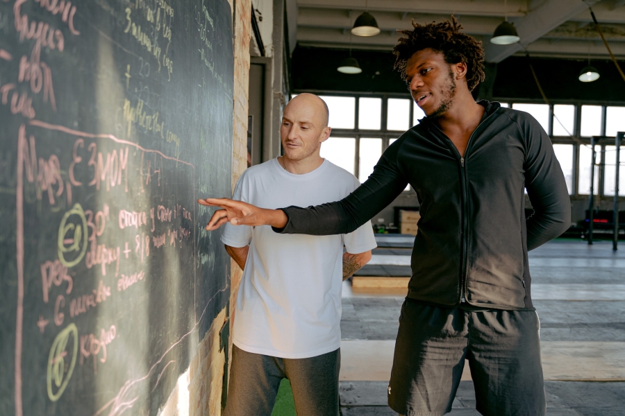 two men standing in front of the blackboard at the gym