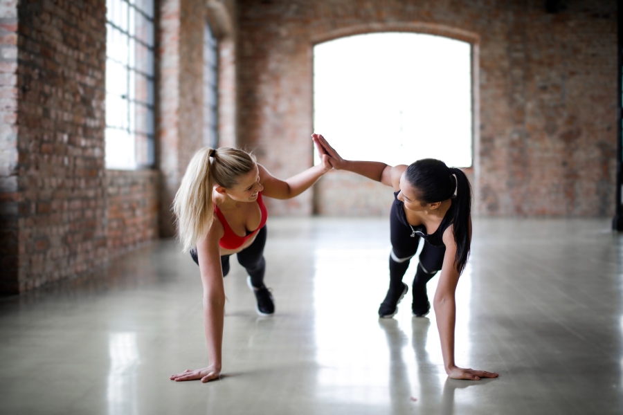 female athletes giving high-five to each other while doing planks