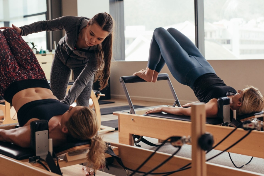 pilates instructor training women at the gym on special equipment