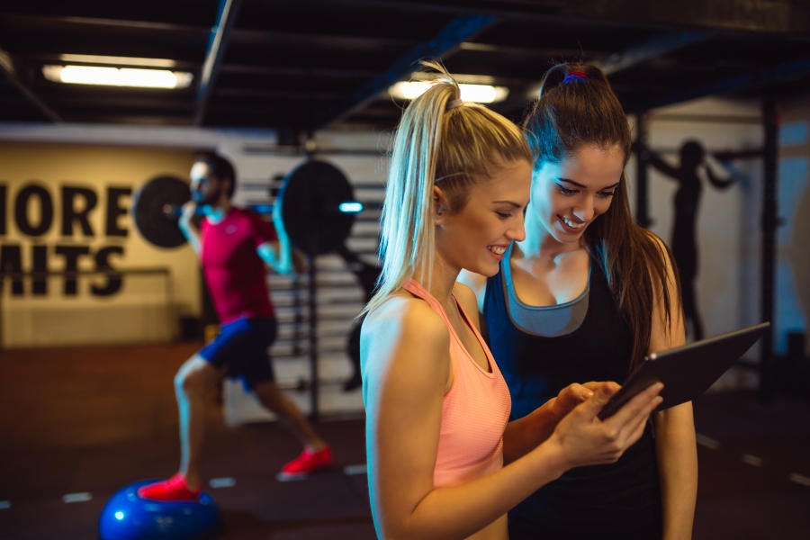 two women at the gym looking at the tablet and smiling