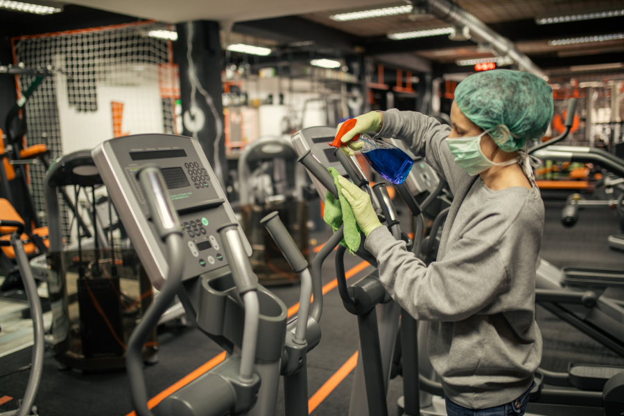 woman cleaning gym equipment