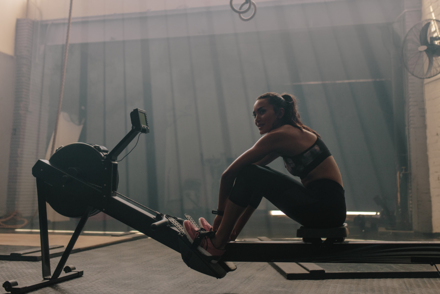 woman resting on a rowing machine in the gym