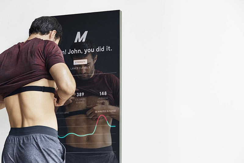 Man comparing his stats via a wearable heart rate sensor via the mirror screen